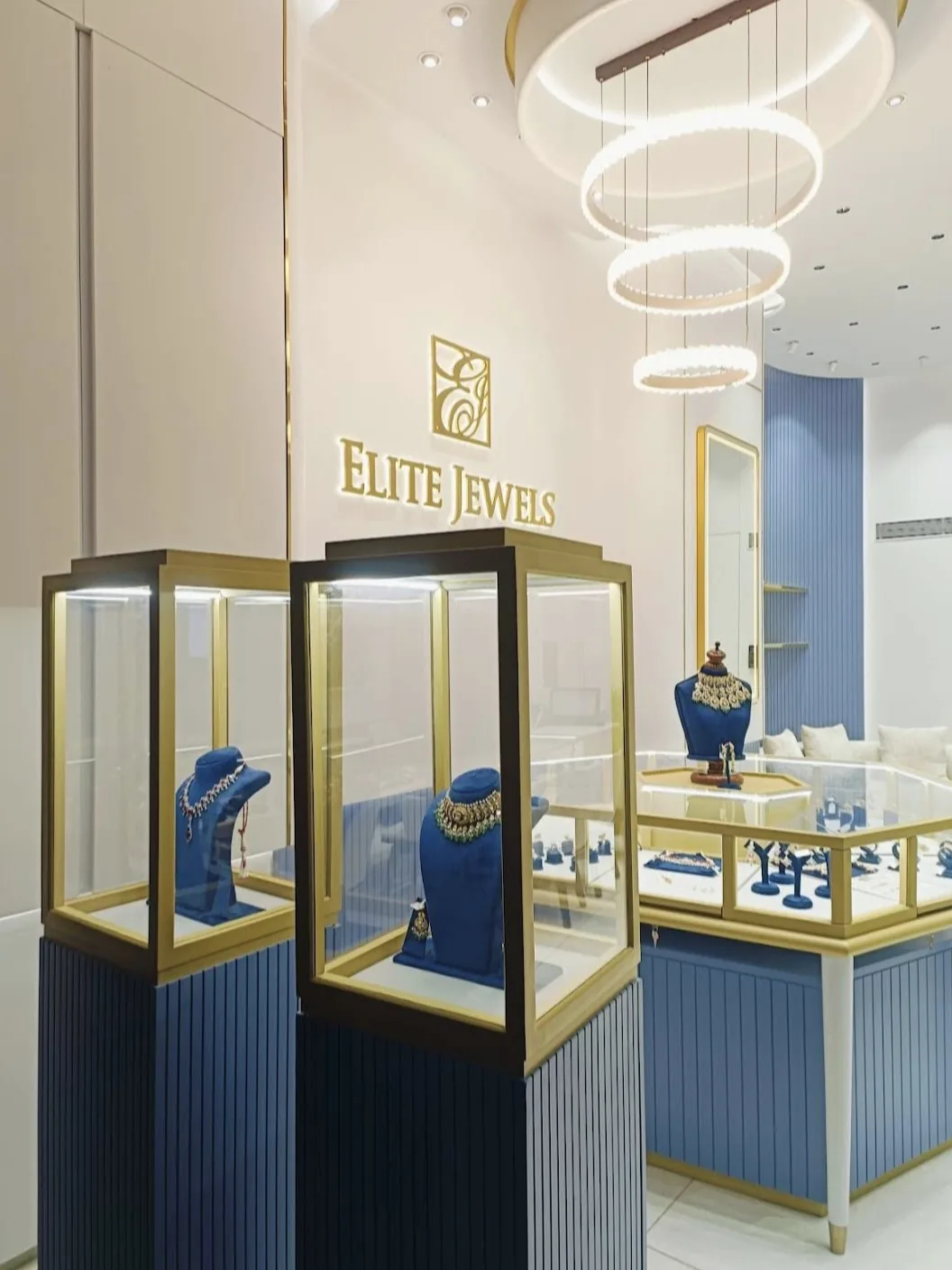 Polki and diamond necklaces in lit glass display cases below the Elite Jewels logo
